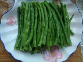 捞出豆角放案板上切成长短相同的段，放入盘内。