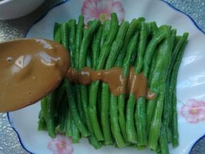 搅拌好的麻酱浇在豆角上，麻酱豆角就做好了。