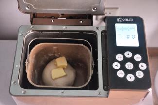 揉至面筋扩展，表面光滑，加入软化的黄油。