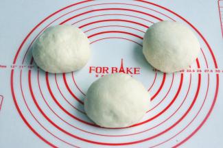 将面团取出，按揉排气后面团均分成三团，盖上保鲜膜松弛15分钟。