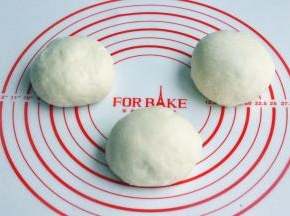 将面团取出，按揉排气后面团均分成三团，盖上保鲜膜松弛15分钟。