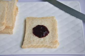 出炉后立即脱模，在晾架上散热，取出后最好先侧放一会儿，以免凹腰，待完全凉透再切片，取一片吐司，抹上草莓桑葚酱。