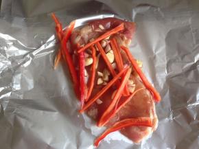 将猪肉片放在锡纸上（哑光面），放上姜、蒜、红葱头和红椒丝。