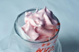 取一个深口杯，放入裱花袋，将中号18齿裱花嘴放入其中，再倒入蛋白霜。