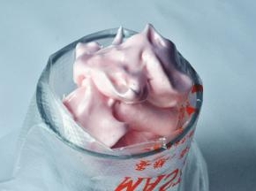 取一个深口杯，放入裱花袋，将中号18齿裱花嘴放入其中，再倒入蛋白霜。