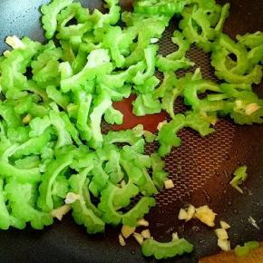 锅中再次加入少油，加入切碎的蒜炒香，再加入苦瓜，加一小勺生抽，盐，煸炒。