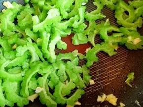 锅中再次加入少油，加入切碎的蒜炒香，再加入苦瓜，加一小勺生抽，盐，煸炒。