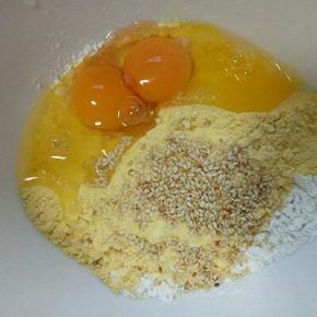 把面粉，玉米粉，熟芝麻，鸡蛋，白砂糖，全部放在一个容器里，(芝麻可以根据自己喜欢，不喜欢可以不放，)