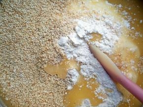 将乳化好的油倒进过筛好的低粉和玉米面里，撒上白芝麻