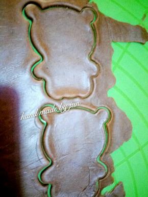 在可可面团上覆盖保鲜膜，用擀面杖擀平，然后用熊猫模具压出熊猫的身体