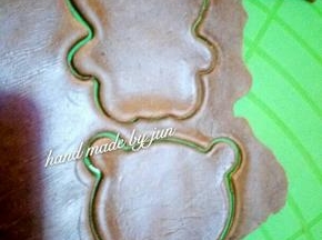 在可可面团上覆盖保鲜膜，用擀面杖擀平，然后用熊猫模具压出熊猫的身体