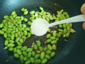 加入毛豆煸炒，炒至毛豆皮微微打皱时加入一勺盐。