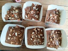 巧克力蛋糕糊装进纸杯，震出气泡。杏仁剪小，放在蛋糕糊表面