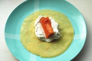 取一个班戟皮，有烙痕的那一面朝上，挖一大勺奶油，放一块木瓜在上面。