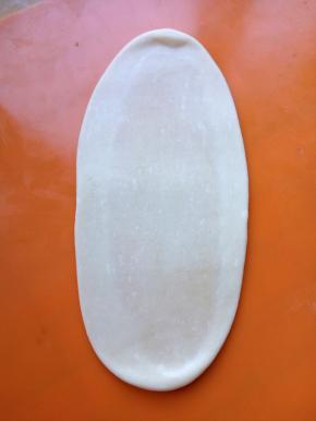 按扁后小心擀成牛舌状，可以看到中间深色的部分就是油酥。擀的时候用力要均匀，以免破皮