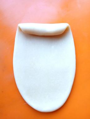 饧好的面卷压扁，擀成长条，再卷成卷。这时的长条更细更长