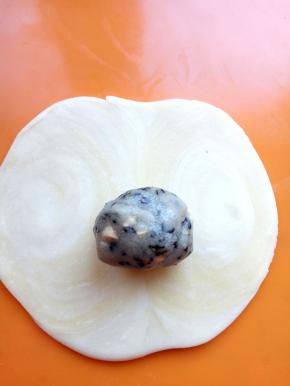 压扁，用擀面杖擀成中间稍厚，四周稍薄的圆饼