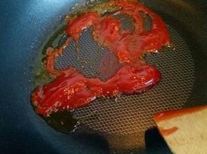 锅中加入适量油，番茄酱煸炒。