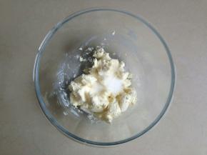 在等待发酵的时间制作奶酪馅，玻璃碗里放入切小块的奶酪，隔热水软化，加入糖。