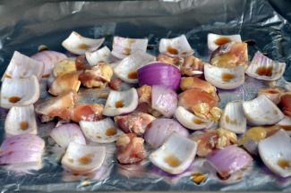 将腌好的鸡脆骨和洋葱放入垫了锡纸的烤盘中，刷上蜂蜜酱油汁。