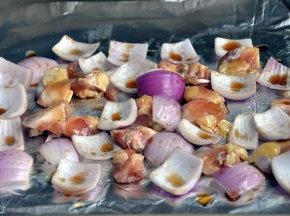 将腌好的鸡脆骨和洋葱放入垫了锡纸的烤盘中，刷上蜂蜜酱油汁。