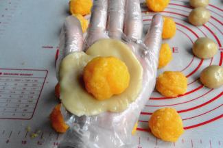 将馅分成30克一个的小球，面团分成20克一个的小球，把皮压薄，包裹馅。配方的量刚好16个50克的慢慢用虎口往上推，捏紧收口，轻轻搓圆月饼。