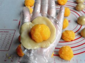 将馅分成30克一个的小球，面团分成20克一个的小球，把皮压薄，包裹馅。配方的量刚好16个50克的慢慢用虎口往上推，捏紧收口，轻轻搓圆月饼。