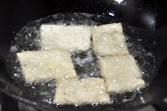 锅中下油，油的用量要比一般炒菜的油多。油热后，将豆腐一片片下锅，中途翻面，但不要频繁翻动，炸至两面颜色金黄，边角起酥，这期间注意火候，不要糊了。