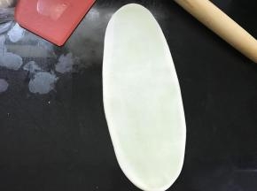 把包入油酥的面团擀成长舌状。