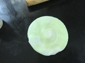 把面卷一切为二，切面朝上擀成圆面片。