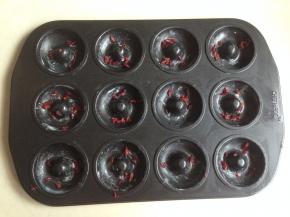 在甜甜圈模具里抹上一层黄油，撒上一些蔓越蔓碎（蔓越莓尽量切碎一些）