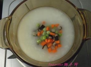 取一碗煮好的大米粥，倒入小锅里，放入豌豆粒、胡萝卜丁和香菇丁，搅拌匀煮一分钟；