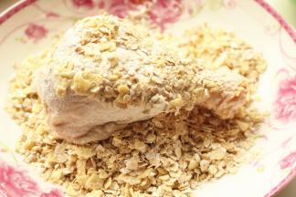 裹粉之后的鸡腿，放进燕麦和薯片里，全身沾满碎片，用手捏一下，牢靠一点。