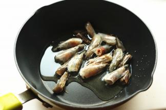 开始熬制虾油。炒锅加油放入虾头开始炒。