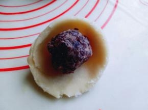 取一块切好的面团，用手掌心压扁，再用擀面杖擀薄，包上蜜豆蛋黄馅，虎口手法包起来，收口朝下，这样步骤及手法全部做完。