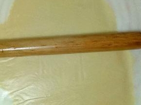 面团上垫上油纸，用擀面杖擀薄，约3mm左右