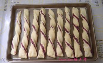 将切好的面条扭成螺纹条依次排入烤盘里，并留出些间隔，包好保鲜膜进行二次醒发一个小时；