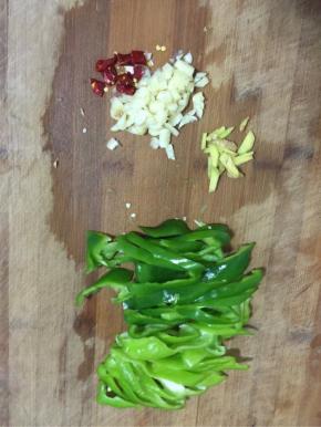 青椒去蒂清洗干净后切成块儿，生姜切成丝，蒜瓣剥皮剁碎，干辣椒切成段备用！
