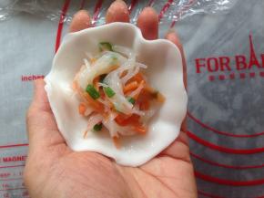 搓成长条，分成每份大概是23克左右的剂子。用擀面杖压成圆形粉皮，中间放入馅料