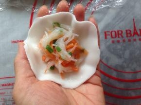 搓成长条，分成每份大概是23克左右的剂子。用擀面杖压成圆形粉皮，中间放入馅料