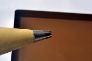 将三能中号18齿花嘴放入裱花袋，套入深口杯，将曲奇面糊倒入裱花袋中，并剪个小口。