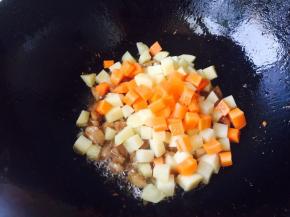 翻炒几下，待鸡腿肉变色后，倒入土豆丁、胡萝卜丁一起翻炒。