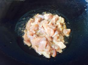 葱段炒出香味后，倒入腌制好的鸡腿肉。