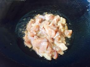 葱段炒出香味后，倒入腌制好的鸡腿肉。