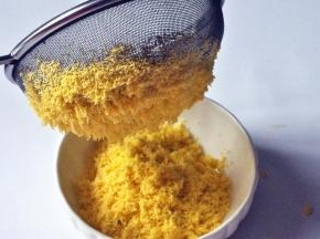 把蛋黄放筛网上，用手指按压，使蛋黄通过筛成蛋黄细末。