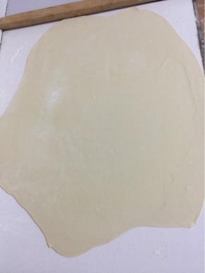 案板上撒少许面粉，面团用擀面杖擀成薄片。

