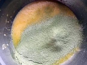 蛋黄里加入玉米油，水，用手动打蛋器搅匀，筛入抹茶低筋面粉，