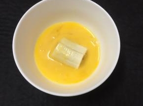 将香蕉段裹上蛋液。