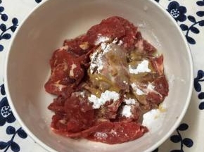 牛肉切薄片放入碗中，加入玉米淀粉、酱油和少许玉米油用手抓匀备用。