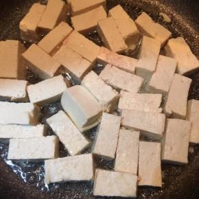 锅中倒入油，大火烧热，下入豆腐转中火煎至呈金黄色。